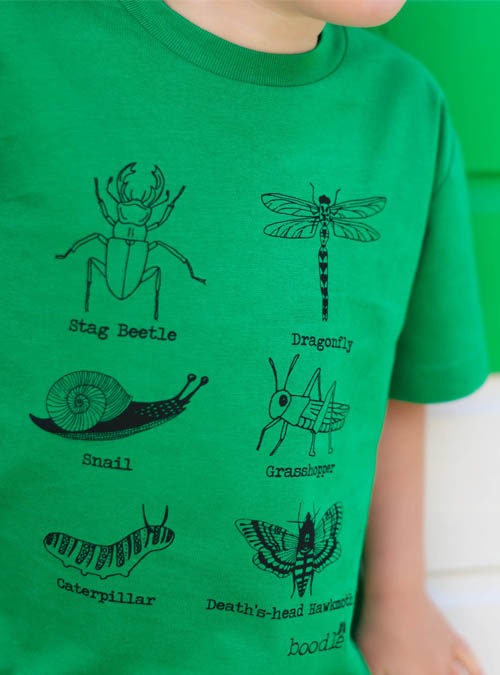 Close up of green kids T-shirt featuring 6 bugs. Organic green cotton with a black illustrative design