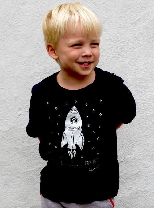 Kid model wearing a navy blue T-shirt with a rocket with white ink on the front