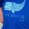 close up of whaley cool kids tee. Blue organic cotton T-shirt featuring a light blue whale