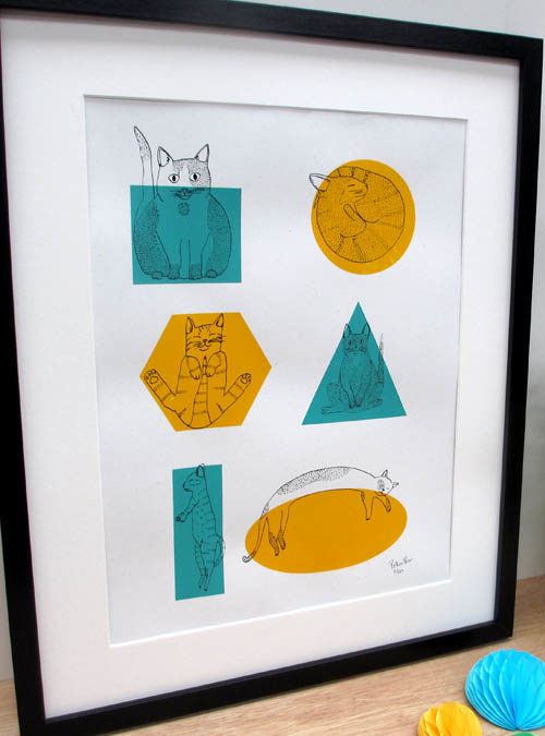 Photo of a cat art print featuring cats fitting into different shapes. Yellow and teal shapes with cats over the top
