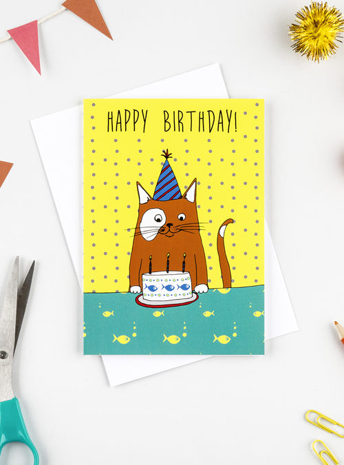 Photograph of a card featuring a ginger cat having a brthday party wearing a party hat and in front of a cake! Yellow spotty background with the wording 'Happy birthday' above