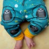 baby wearing teal owl leggings. Teal leggings with a repeat pattern of baby owls with a yellow cuff
