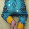 Photo of owl baby leggings from the back. Owl repeat pattern on a teal background showing how they fit on the babys bum.
