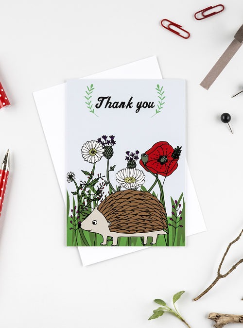 Hedgehog card featuring an illustration of a hedgehog with british flowers in the background and the text 'Thank you' above