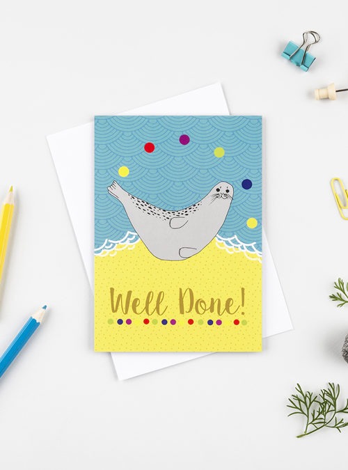 well done seal card featuring a juggling seal on a beach with the text "well done" underneath