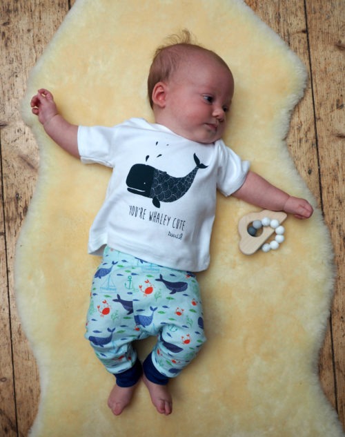 Photo of a baby wearing whale baby leggings and a whale baby T-shirt. Blue leggings featuring nautical images paired with a whale T-shirt with the text 'You're whaley cute' T-shirt