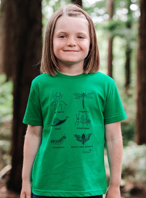 Model wearing kids green T-shirt featuring 6 green bugs. Organic green cotton with a black illustrative print