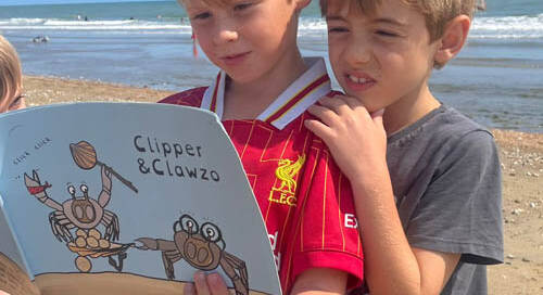 3 boys reading Clipper and Clawzo on the beach