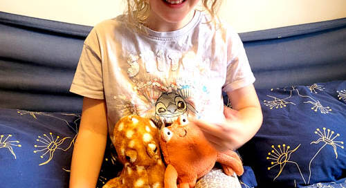 Child reading Clipper and Clawzo holding 2 cuddly toys