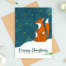 Fox and firefly Christmas card sitting on a brown envelope with festive props