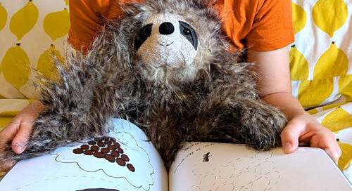 young girl reading book Sloth Moth with a sloth toy