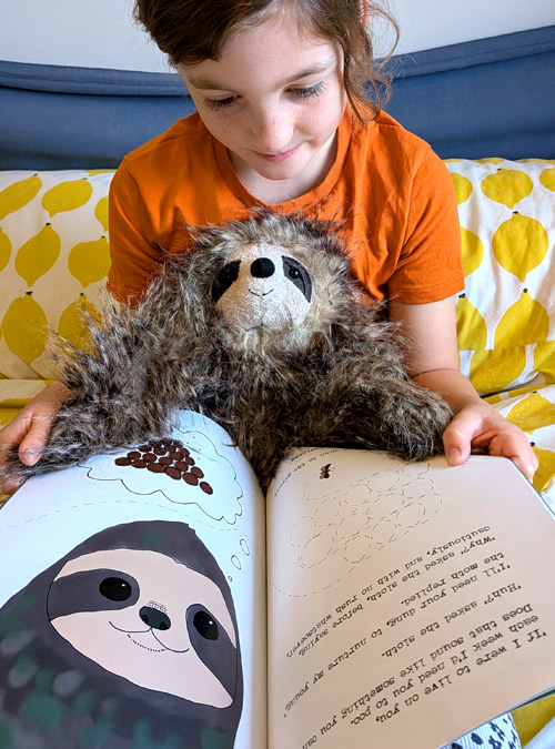 young girl reading book Sloth Moth with a sloth toy